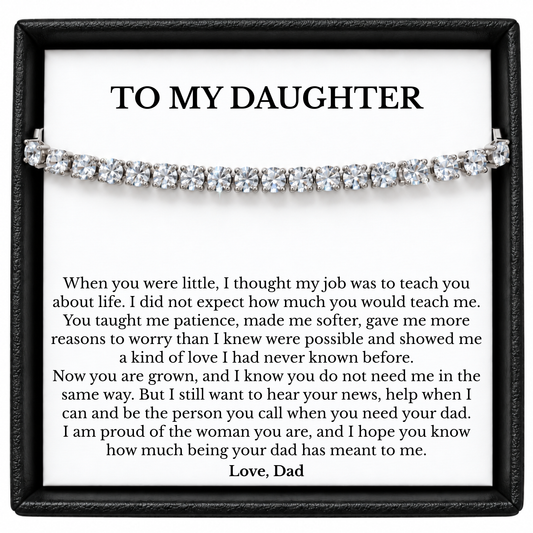 Silver-coloured tennis bracelet across a To My Daughter message card signed Love, Dad, inside a black gift box.