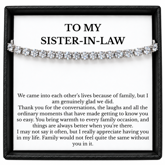 Tennis bracelet with clear round stones across a sister-in-law message card inside a black gift box.