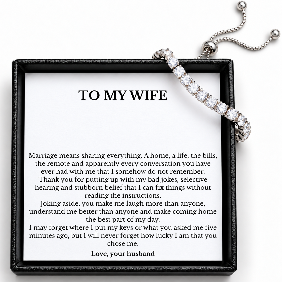 Tennis bracelet draped over the To My Wife message card, showing the adjustable slider, chain ends and clear round stones.