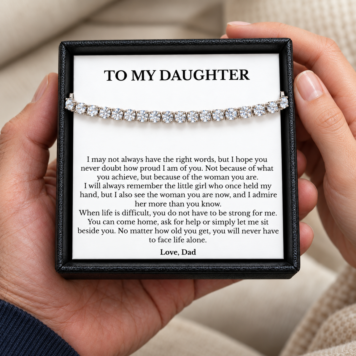 Hands holding a black gift box with a tennis bracelet and a To My Daughter message card signed Love, Dad.