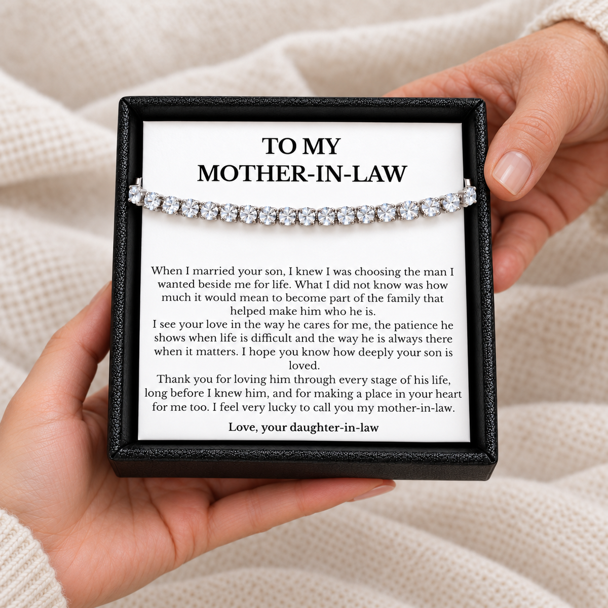 Hands holding an open black gift box with a tennis bracelet and heartfelt mother-in-law message card from her daughter-in-law.
