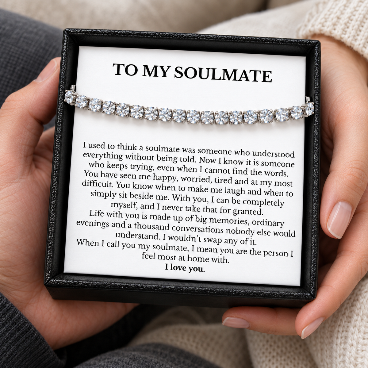 Hands holding an open black gift box containing a tennis bracelet and a heartfelt To My Soulmate message card.