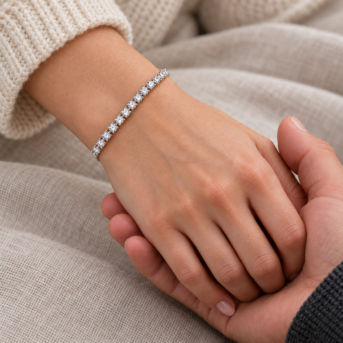 Close-up of a silver tone tennis bracelet with clear round stones worn on a wrist.