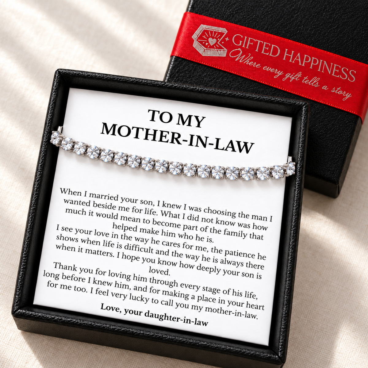Mother-in-law bracelet and message card in an open black gift box beside its lid with Gifted Happiness red ribbon.