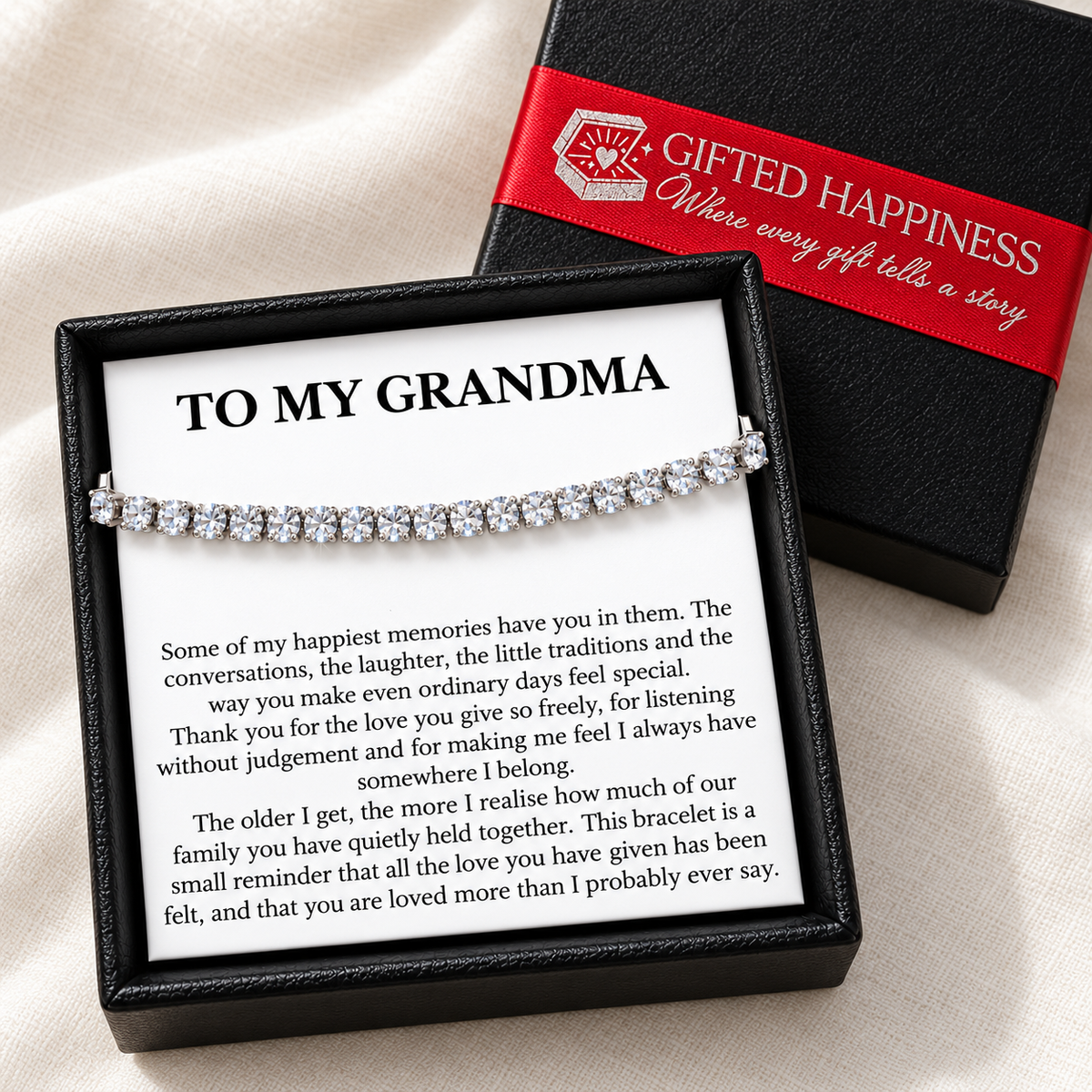 Grandma tennis bracelet and heartfelt message card in a black gift box beside the lid with Gifted Happiness red ribbon.