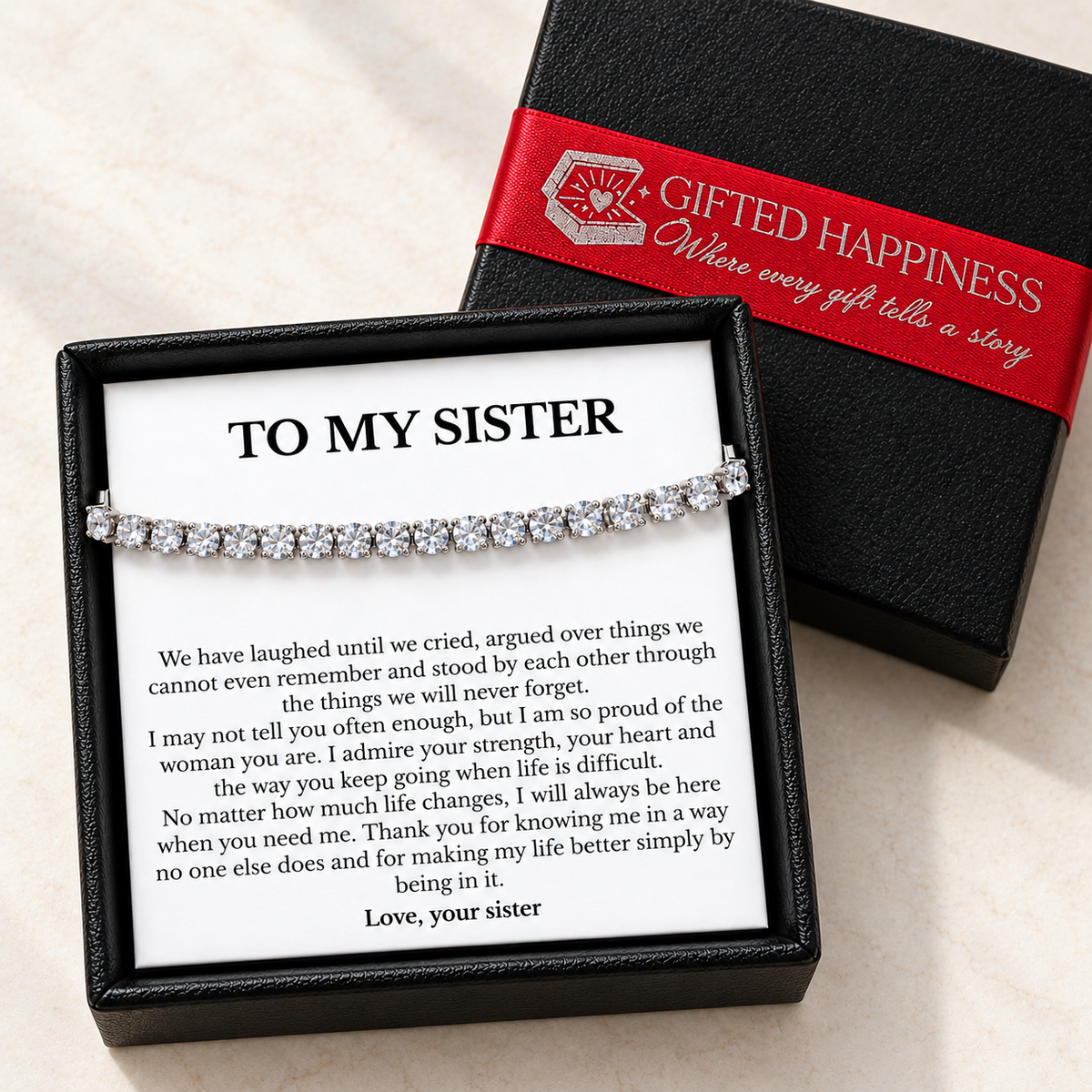 Sister bracelet and printed message card in an open black gift box beside its lid with Gifted Happiness red ribbon.