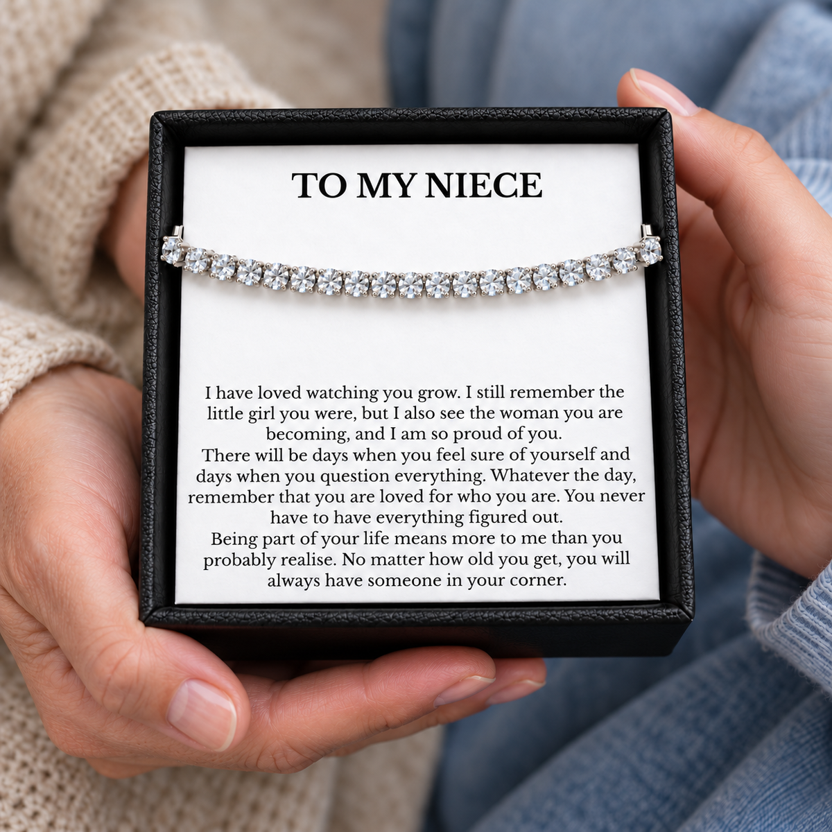 Hands holding a black gift box containing a silver-coloured tennis bracelet and a To My Niece message card.